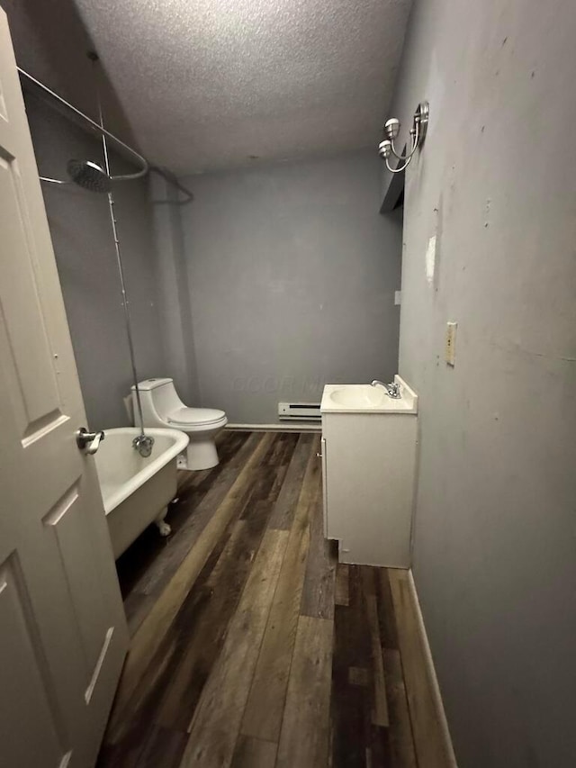 bathroom with toilet, wood-type flooring, a textured ceiling, vanity, and a bath