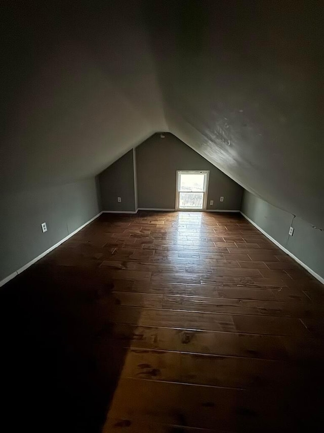 bonus room with dark wood-type flooring and vaulted ceiling