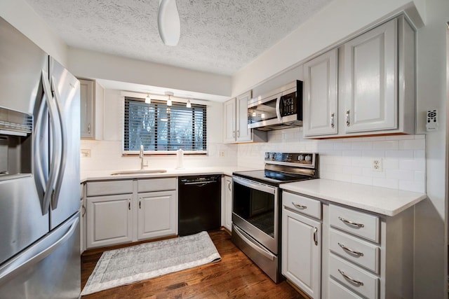 kitchen with dark wood-type flooring, sink, gray cabinets, stainless steel appliances, and backsplash