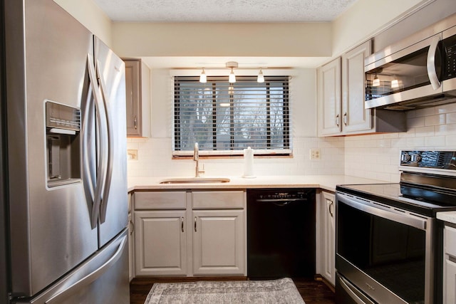 kitchen with appliances with stainless steel finishes, sink, backsplash, and a textured ceiling