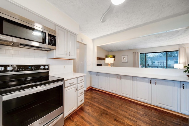 kitchen with tasteful backsplash, white cabinetry, dark hardwood / wood-style flooring, stainless steel appliances, and a textured ceiling