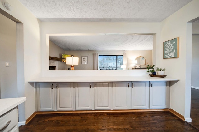 bar with white cabinetry, dark wood-type flooring, and a textured ceiling