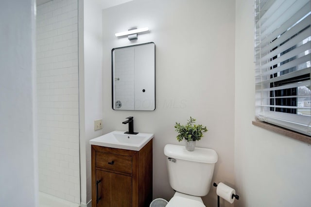 bathroom featuring tiled shower, vanity, and toilet