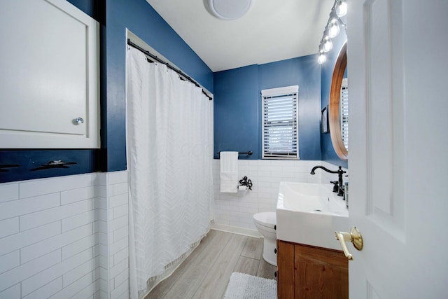 bathroom with tile walls, vanity, wood-type flooring, and toilet