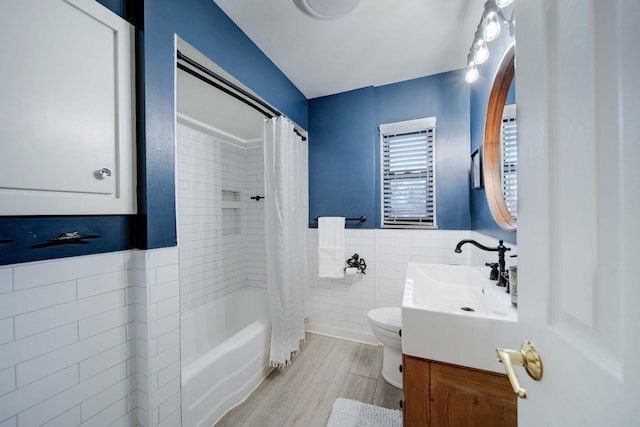 full bathroom featuring toilet, wood-type flooring, tile walls, vanity, and shower / bath combo with shower curtain