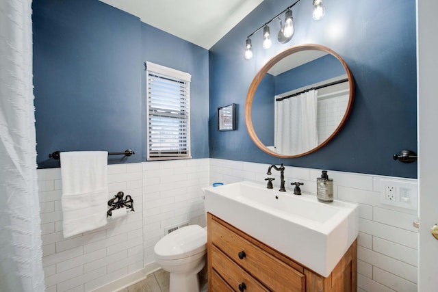 bathroom featuring vanity, tile walls, and toilet