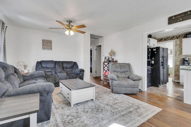 living area featuring light wood finished floors, baseboards, and a ceiling fan