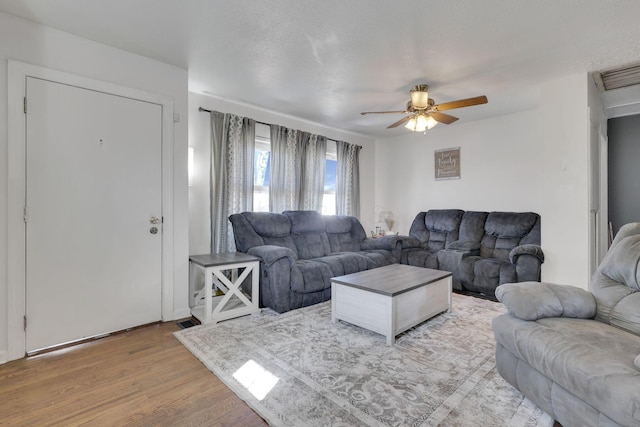 living area featuring ceiling fan, a textured ceiling, and light wood-style flooring