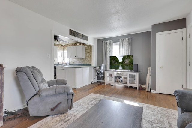 living room with a textured ceiling, baseboards, and wood finished floors