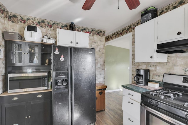 kitchen featuring white cabinetry, appliances with stainless steel finishes, ventilation hood, dark countertops, and glass insert cabinets