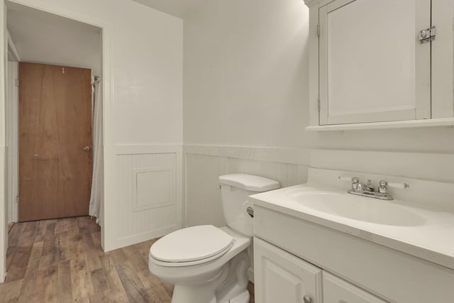 bathroom featuring wainscoting, vanity, toilet, and wood finished floors