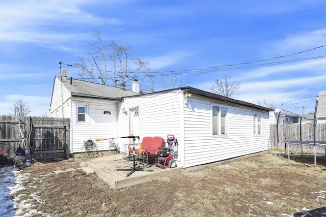 rear view of house with a patio area, a trampoline, and fence