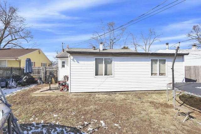 back of property with a trampoline and fence