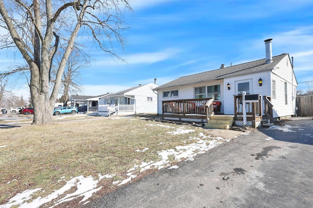 single story home with a front lawn and a wooden deck