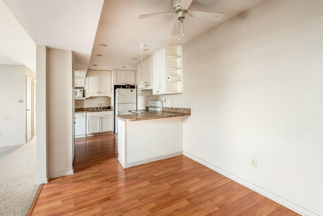 kitchen with sink, white cabinetry, kitchen peninsula, white appliances, and light hardwood / wood-style floors