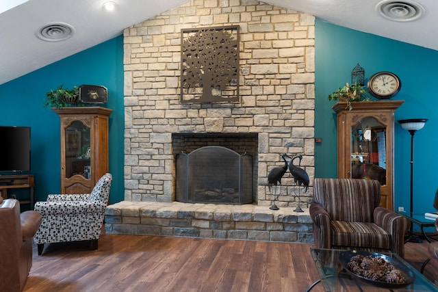 living room with lofted ceiling, dark hardwood / wood-style flooring, and a stone fireplace