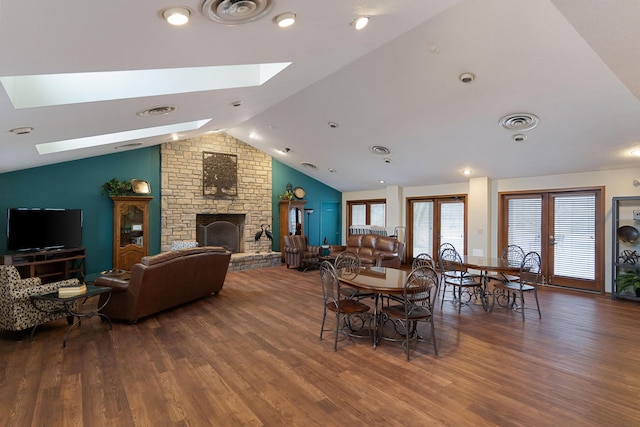 dining space featuring dark hardwood / wood-style flooring, a fireplace, french doors, and vaulted ceiling with skylight