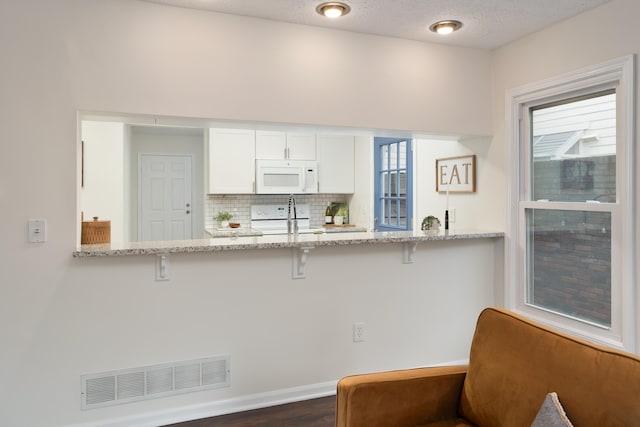 kitchen with sink, light stone counters, tasteful backsplash, white appliances, and white cabinets