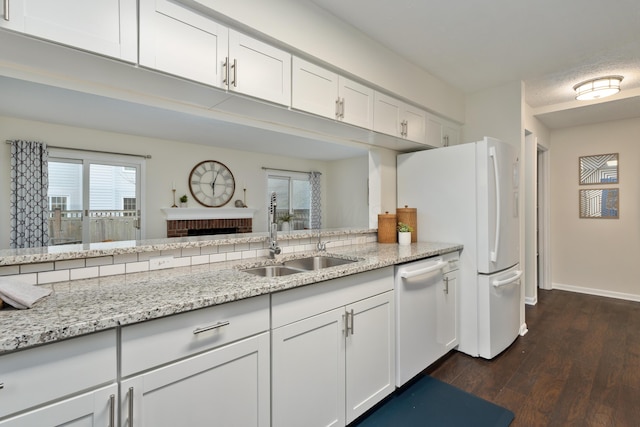 kitchen featuring white cabinetry, white dishwasher, light stone countertops, and sink