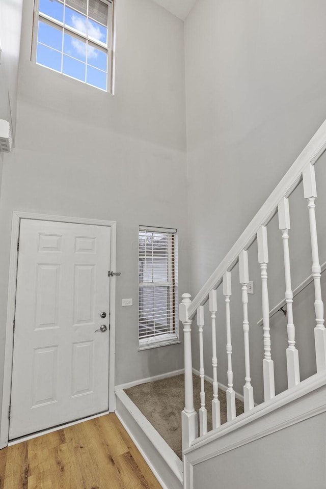 entrance foyer with hardwood / wood-style floors and a towering ceiling