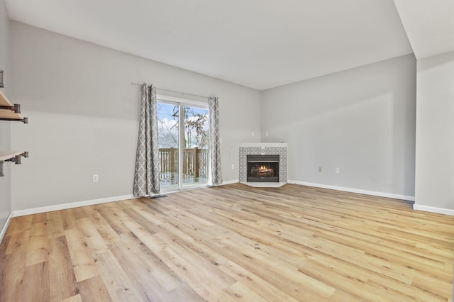 unfurnished living room featuring a tile fireplace and light wood-type flooring