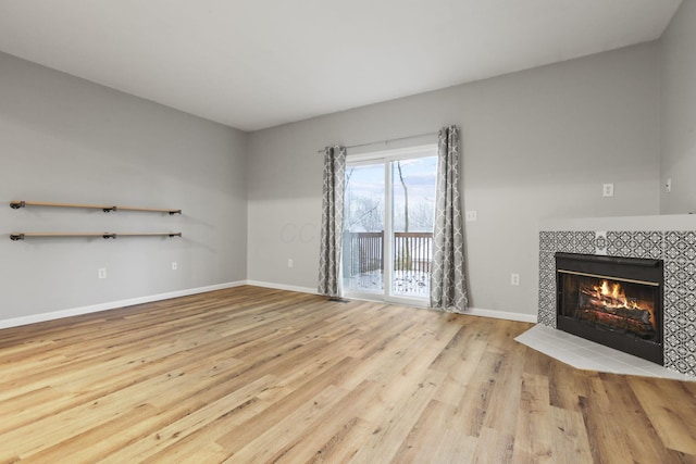 unfurnished living room featuring a tiled fireplace and light wood-type flooring