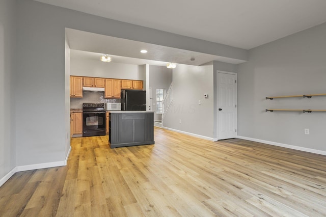 kitchen featuring tasteful backsplash, a center island, light hardwood / wood-style flooring, and black appliances