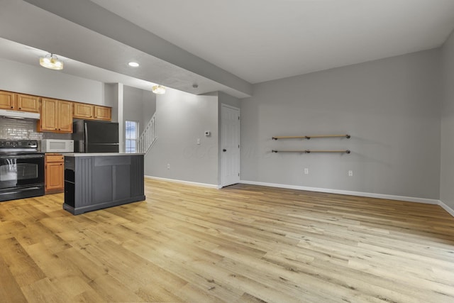 kitchen featuring backsplash, a breakfast bar area, black appliances, and light hardwood / wood-style floors