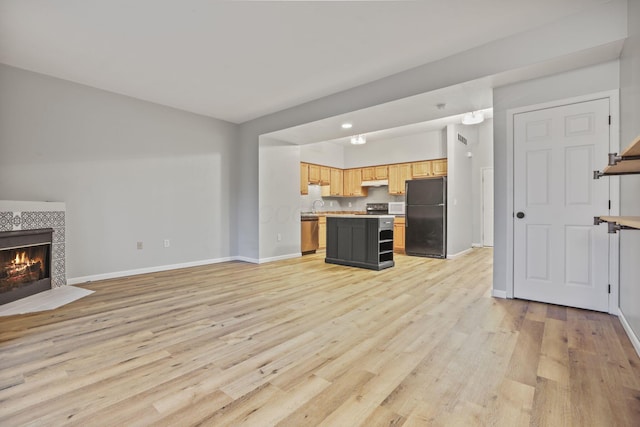 unfurnished living room with a fireplace, sink, and light wood-type flooring