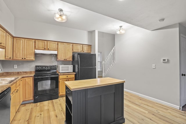 kitchen featuring sink, light wood-type flooring, decorative backsplash, and black appliances