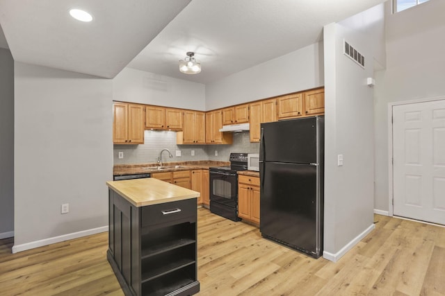 kitchen with sink, light hardwood / wood-style flooring, black appliances, a kitchen island, and decorative backsplash