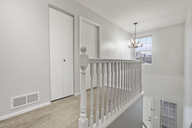 corridor featuring an inviting chandelier and light colored carpet