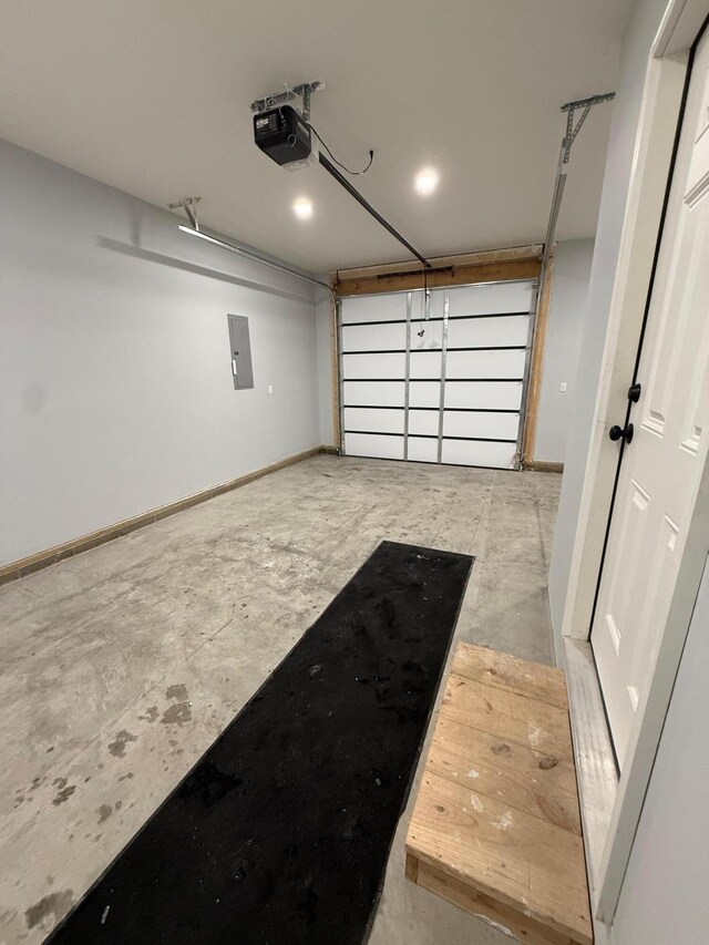 garage featuring a garage door opener, electric panel, and baseboards