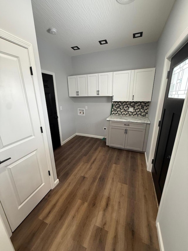 clothes washing area with washer hookup, cabinet space, dark wood-type flooring, a textured ceiling, and baseboards