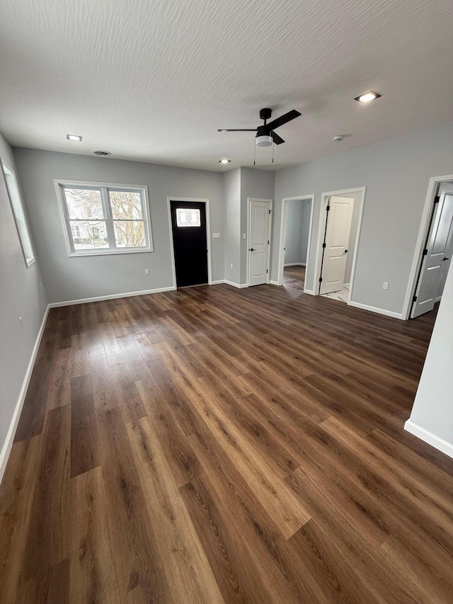 unfurnished living room featuring a ceiling fan, dark wood finished floors, a textured ceiling, and baseboards