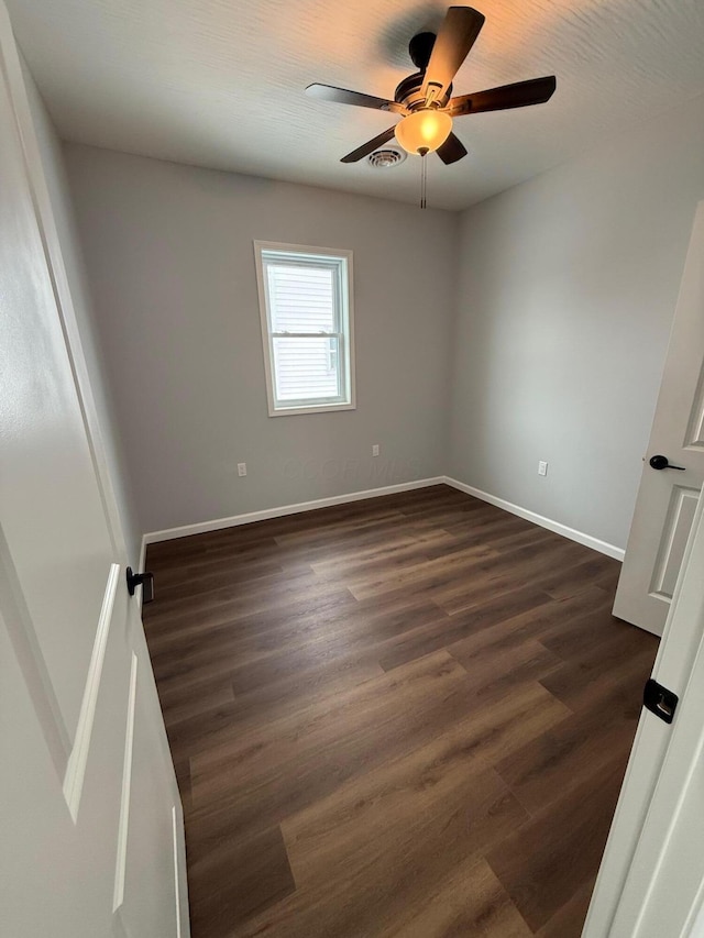 unfurnished room featuring visible vents, baseboards, ceiling fan, and dark wood-type flooring