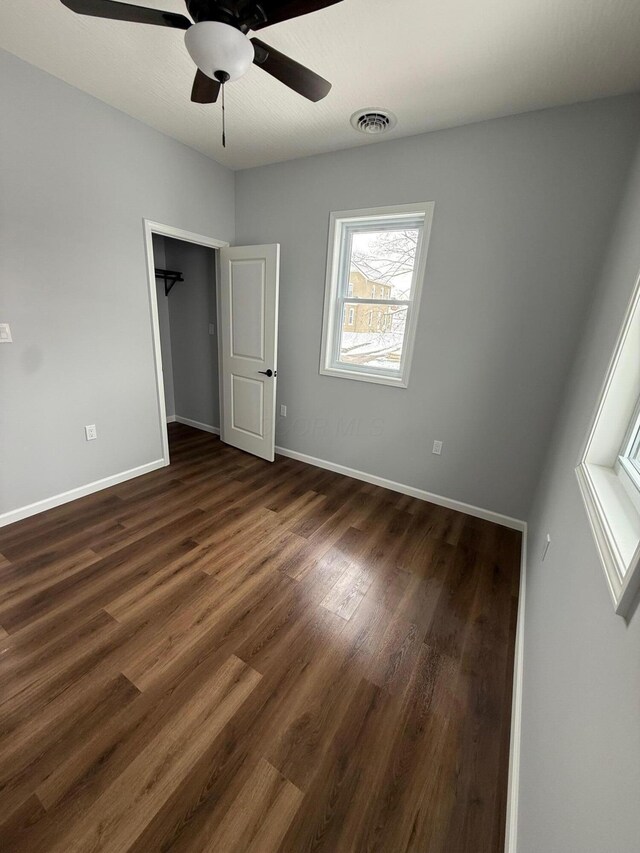 unfurnished bedroom featuring dark wood-style floors, ceiling fan, visible vents, and baseboards