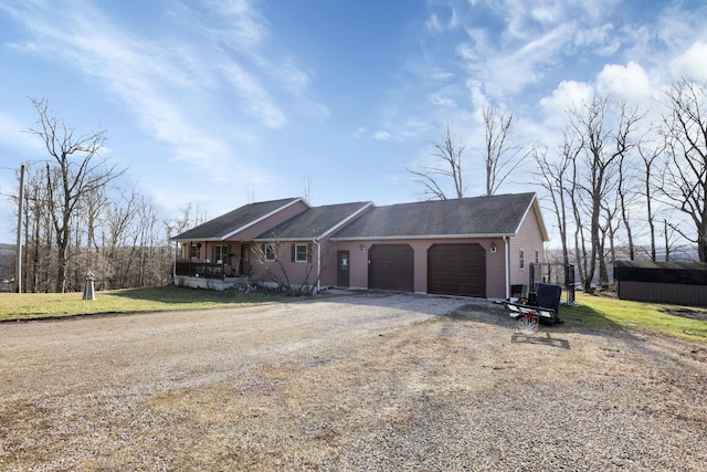 ranch-style home with a front lawn, covered porch, driveway, and an attached garage