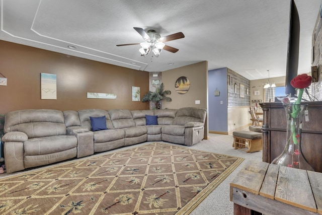 carpeted living room featuring baseboards, a textured ceiling, and ceiling fan with notable chandelier