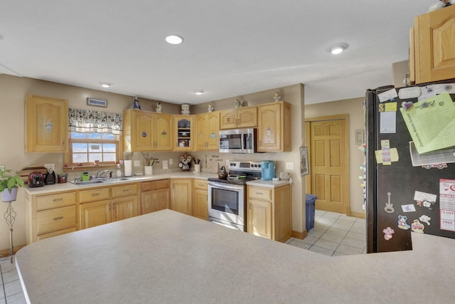 kitchen with glass insert cabinets, appliances with stainless steel finishes, light countertops, and light brown cabinetry