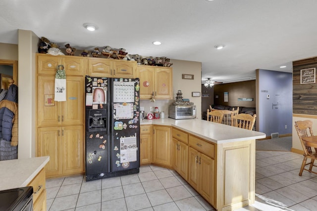 kitchen with a peninsula, range with electric cooktop, light countertops, and black fridge