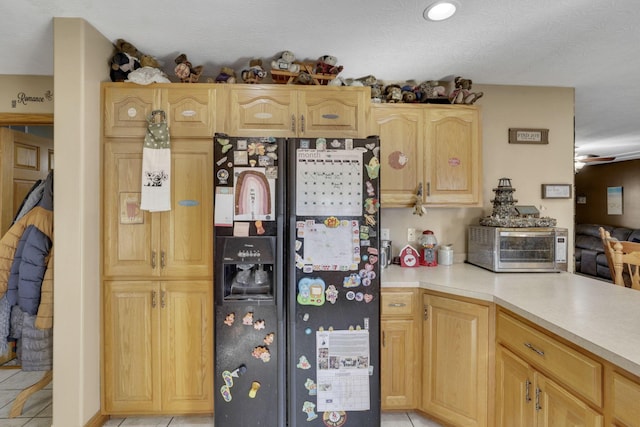 kitchen featuring light tile patterned floors, black refrigerator with ice dispenser, light countertops, and light brown cabinetry