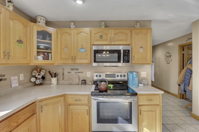 kitchen featuring light brown cabinets, glass insert cabinets, stainless steel appliances, and light countertops