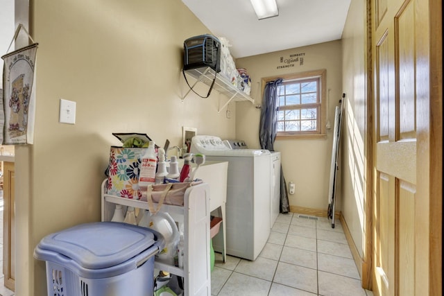 clothes washing area featuring washing machine and dryer, laundry area, baseboards, and light tile patterned floors