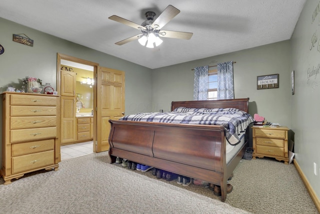 bedroom with a textured ceiling, connected bathroom, light colored carpet, a ceiling fan, and baseboards