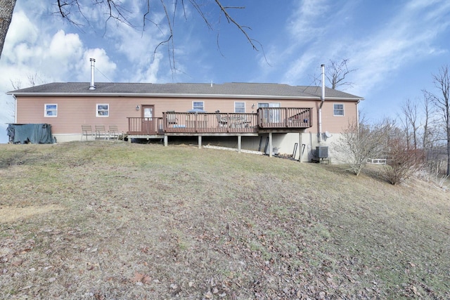 rear view of property featuring a deck, a lawn, and central air condition unit