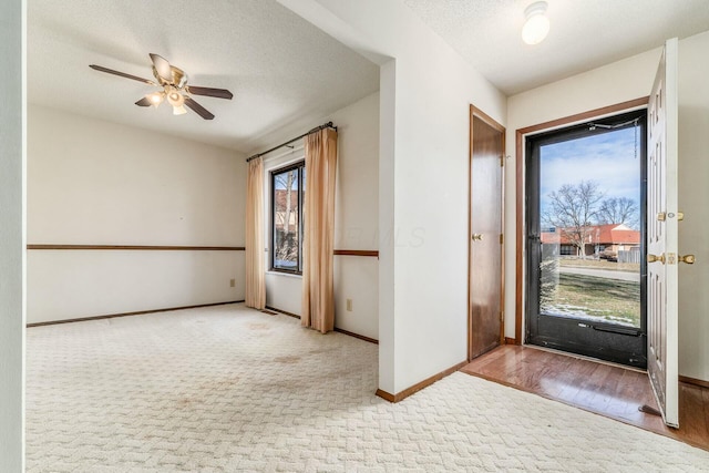 carpeted entrance foyer featuring ceiling fan and a textured ceiling