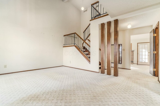 unfurnished living room with a high ceiling and light carpet