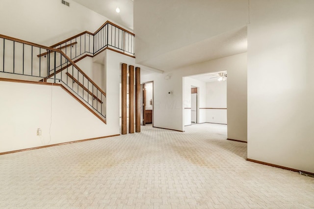 unfurnished living room featuring ceiling fan, a high ceiling, and carpet flooring