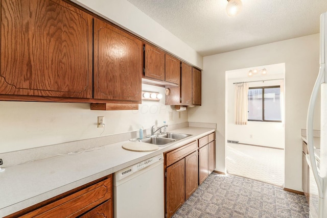 kitchen with light colored carpet, white appliances, sink, and a textured ceiling